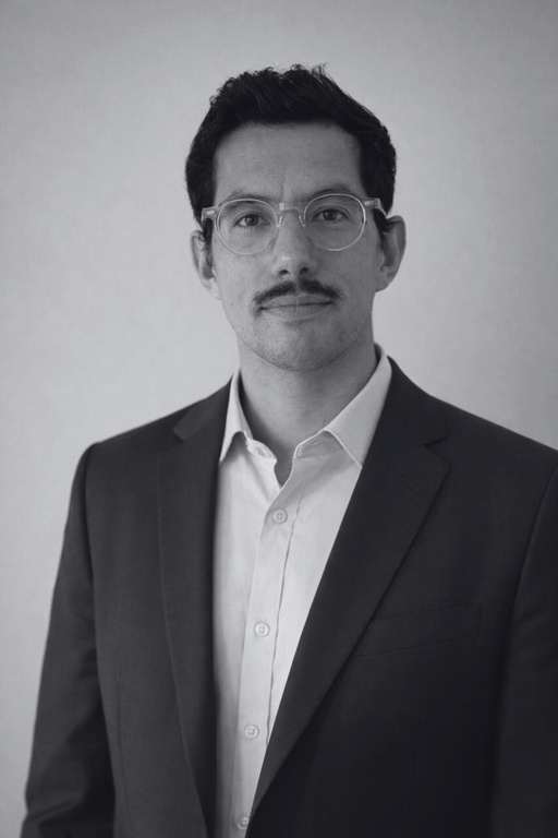 Portrait en noir et blanc d'Arthur Paris, en costume et chemise ouverte, sur fond clair.