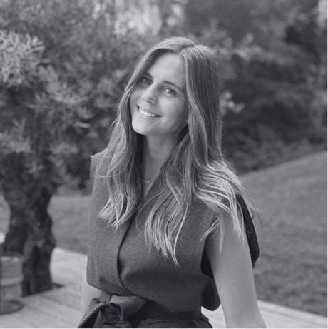 Portrait en noir et blanc de Clara André, souriante, devant un olivier.
